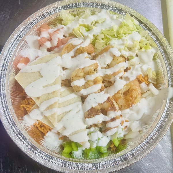 Carytown Gyro's shrimp bowl with rice, lettuce, pita, and white sauce in a foil container.