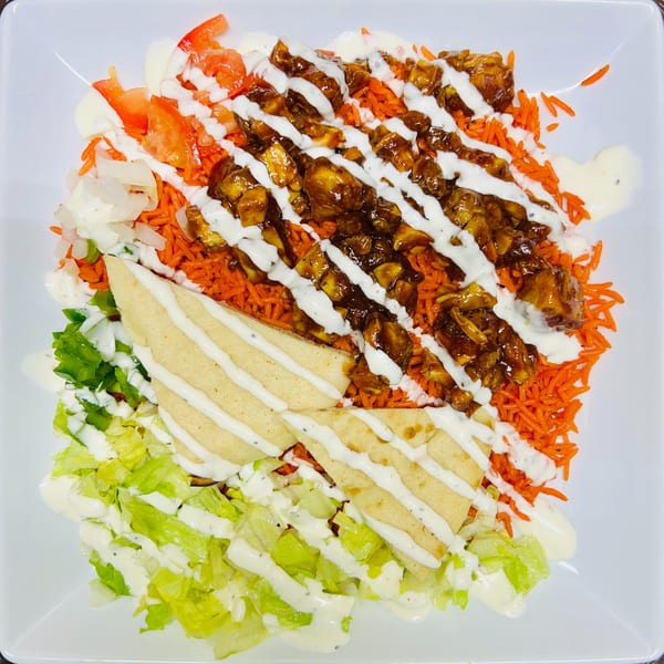Carytown Gyro's chicken and rice platter with lettuce, tomatoes, onions, pita, and white sauce.