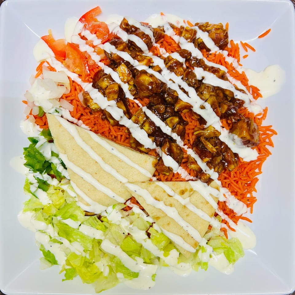 Carytown Gyro's chicken and rice platter with lettuce, tomatoes, onions, pita, and white sauce.